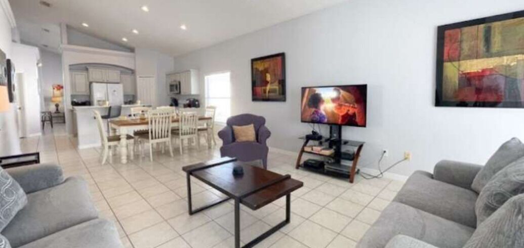 Una sala de estar moderna con comedor, televisor de pantalla plana y obras de arte en las paredes.