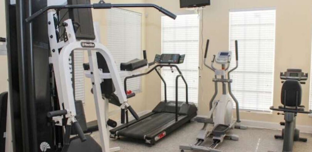 Une salle de sport équipée de machines de cardio, de machines de musculation et d’un tapis de course.