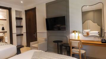 Una habitación de hotel con cama, escritorio, silla, televisión y espejo.