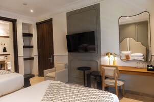 Una habitación de hotel con cama, escritorio, silla, televisión y espejo.