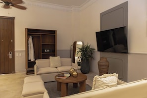 Suite, 2 grands lits, balcon | Coin séjour | TV connectée de 55 pouces avec chaînes par satellite