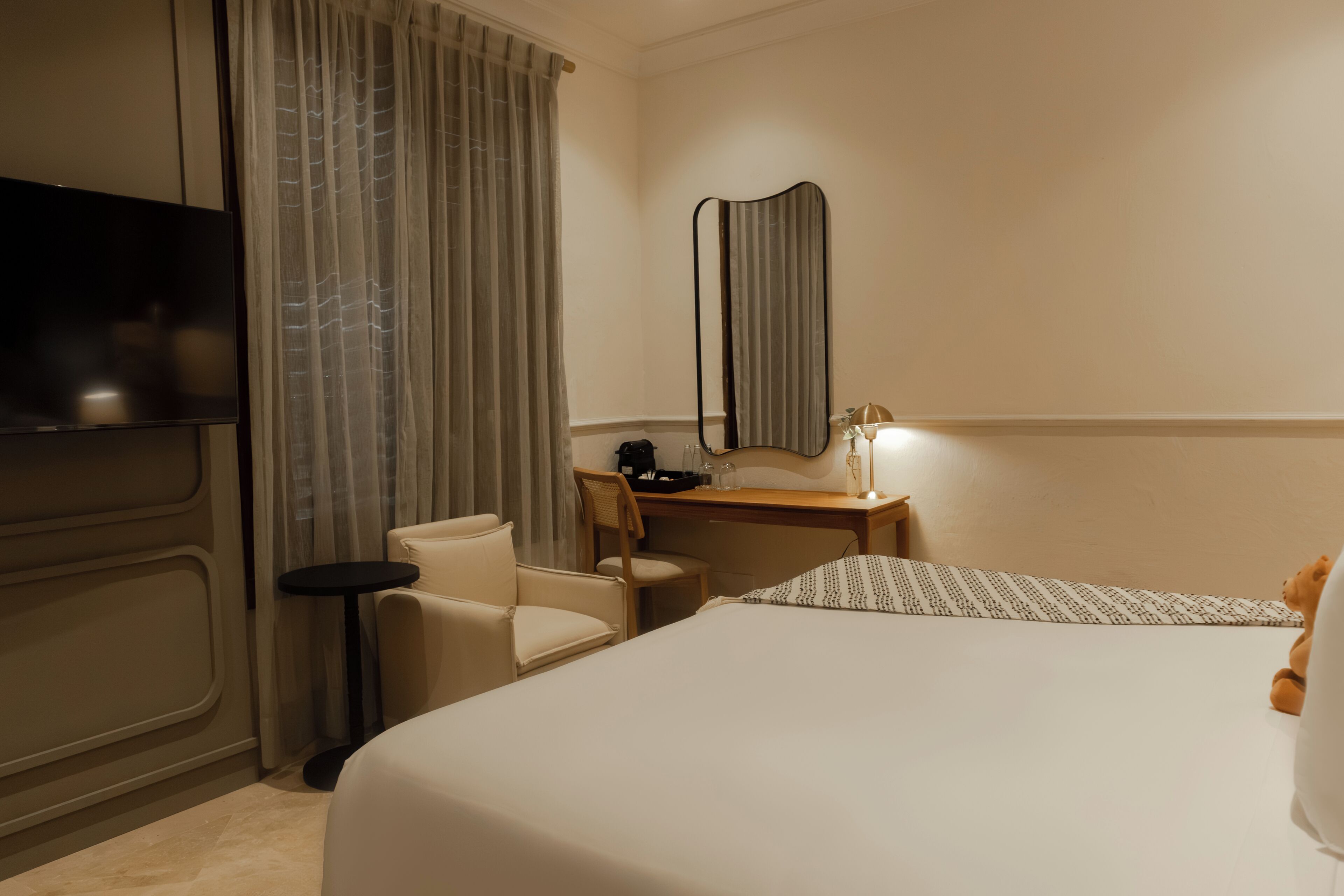 Ein Hotelzimmer mit Bett, Schreibtisch, Stuhl, Fernseher und Spiegel.