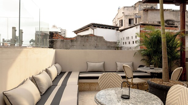 Una terraza en la azotea con un sofá, sillas y una mesa.