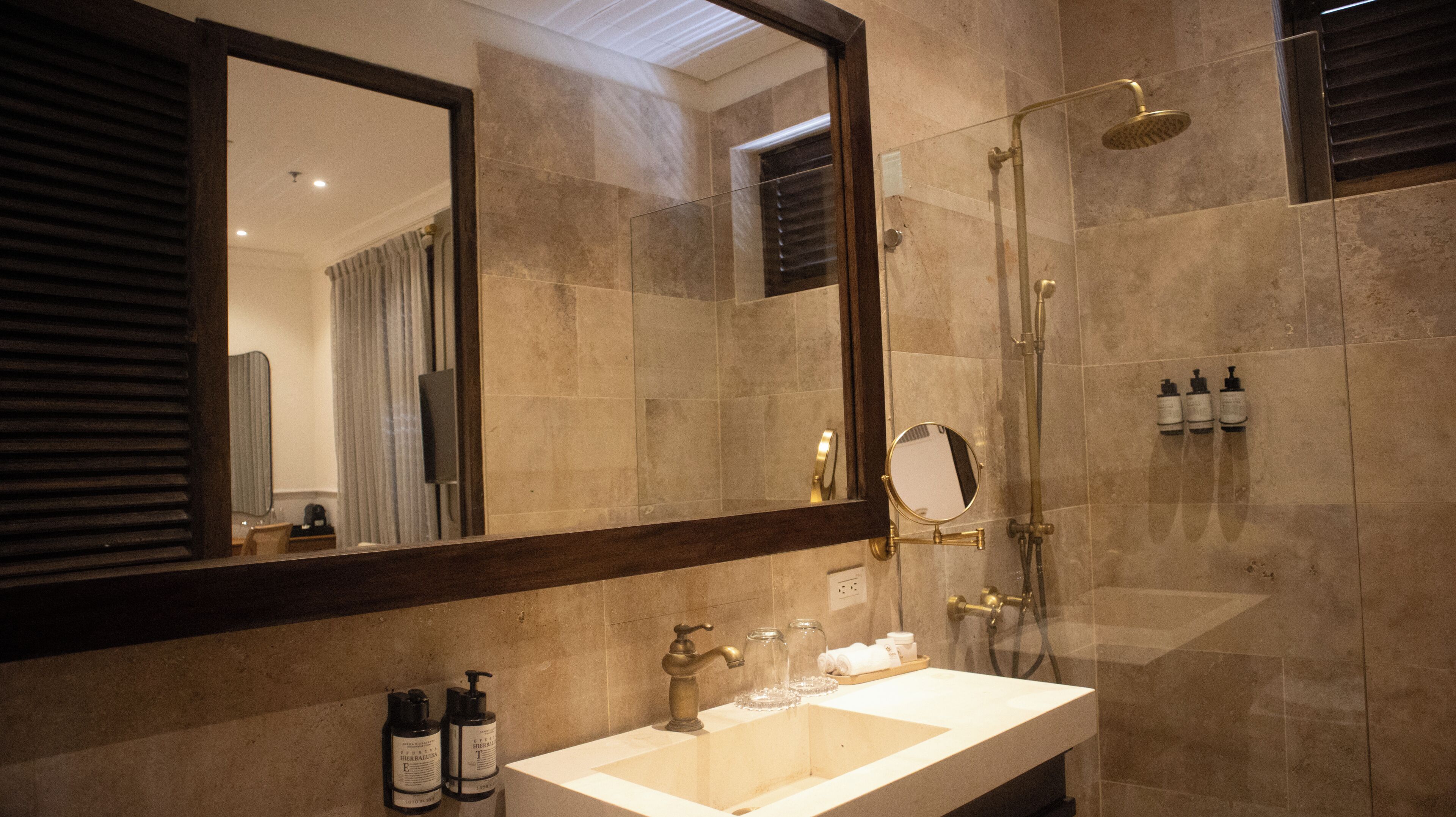 Un baño moderno con un espejo grande, un lavamanos, una ducha y artículos de aseo.