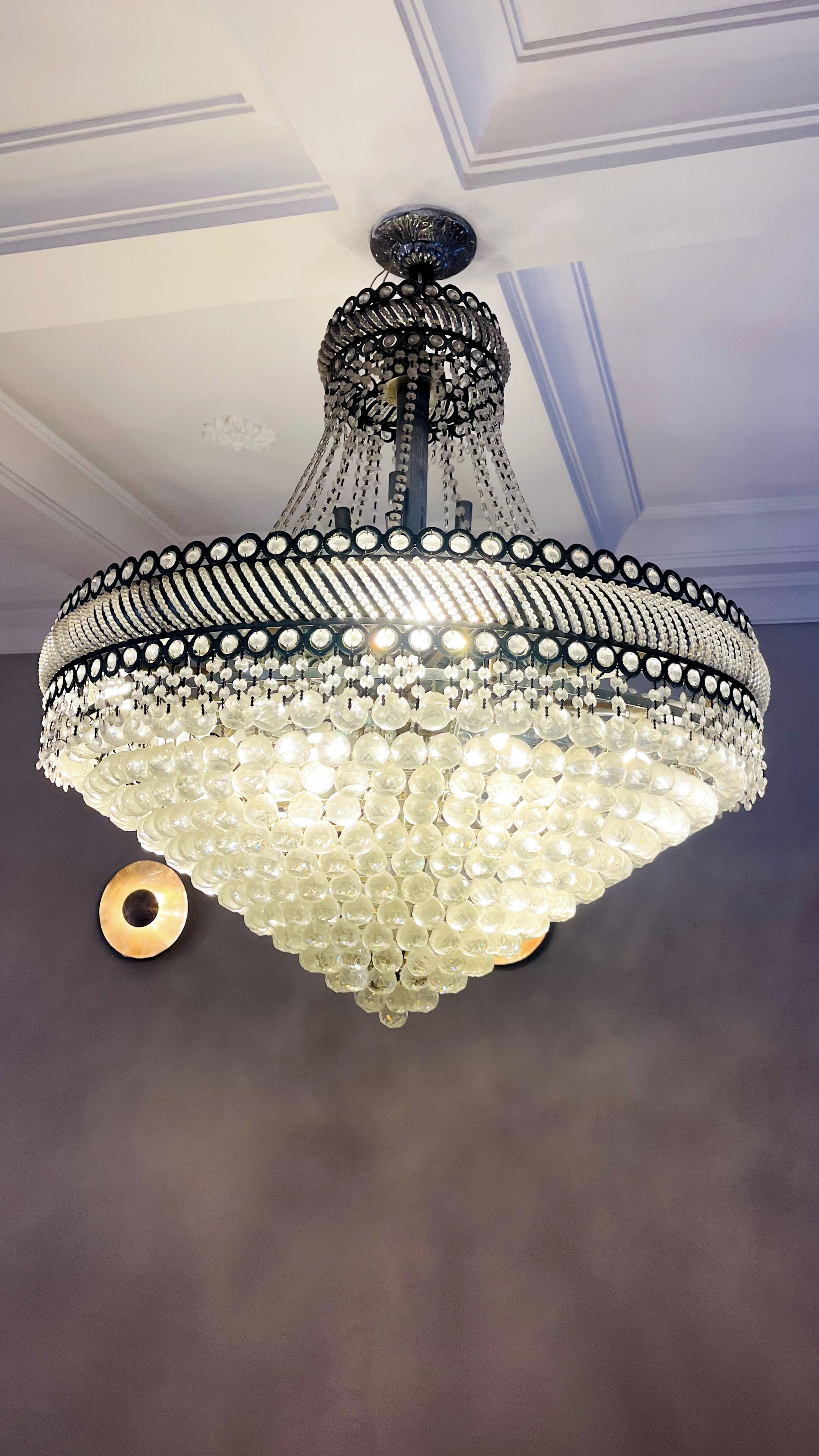 A chandelier with multiple tiers of clear crystal and black metal accents.