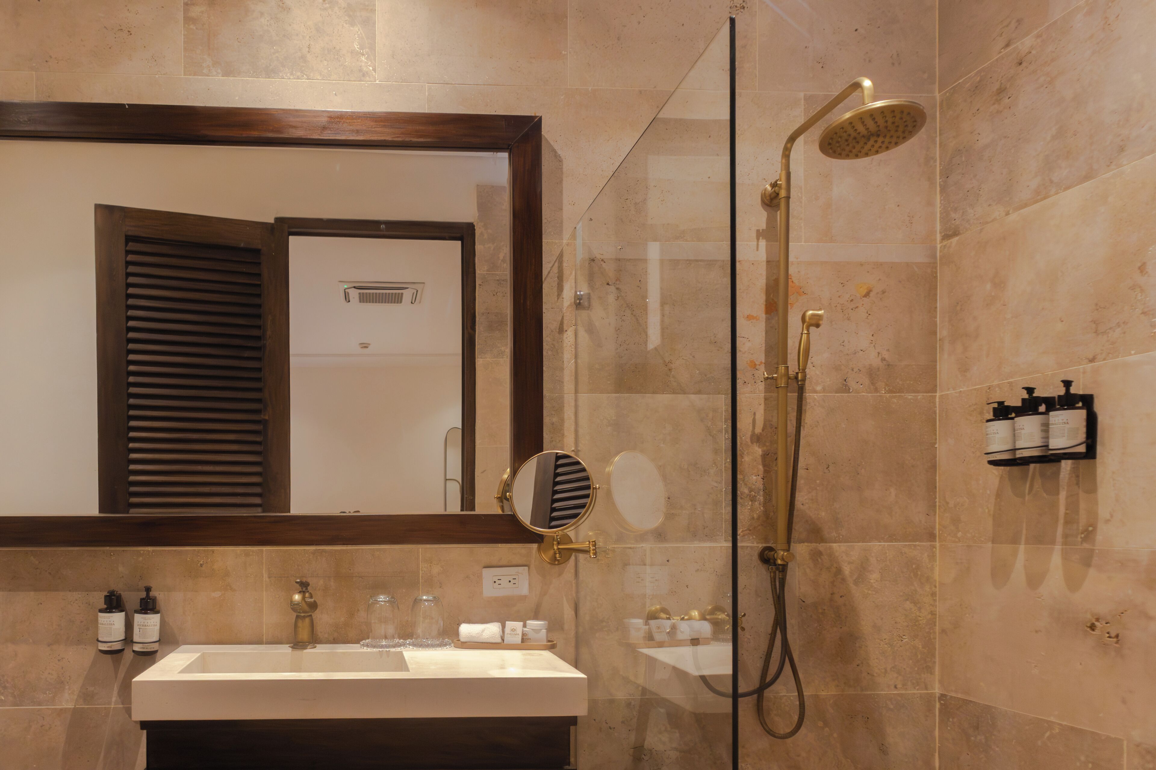 A bathroom with a shower, sink, mirror, and toiletries.