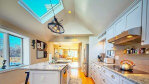 A modern kitchen with a central island, wooden flooring, and a skylight. - Chatham Family Retreat w/ Heated Pool (Chatham)
