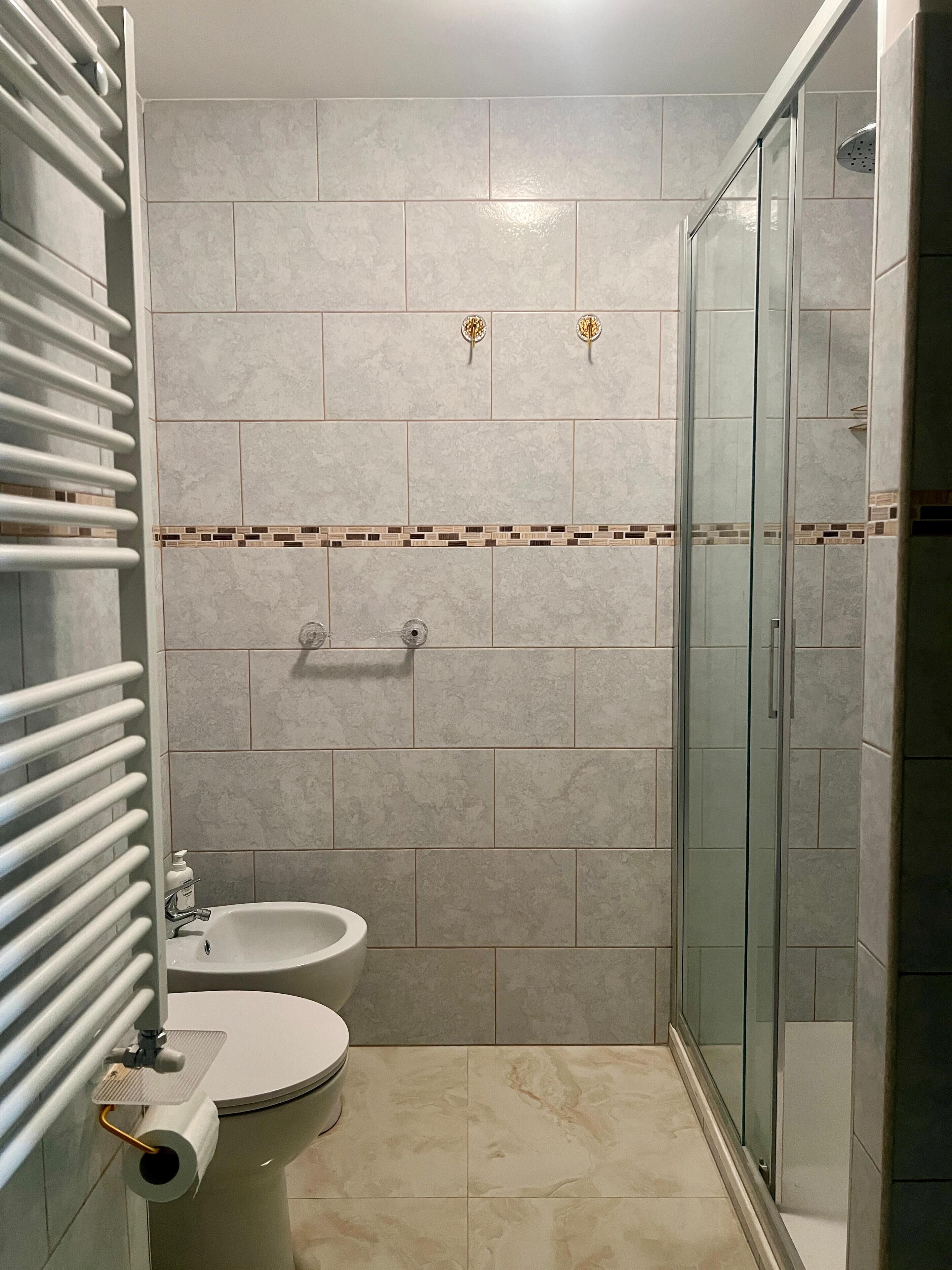 Un bagno con il water, un bidet e una cabina doccia in vetro.