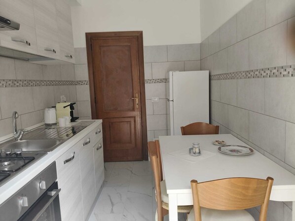 A compact kitchen with a stove, sink, and a dining table with chairs. - Delightful Rome apartment -Vatican 9' from the Battistini metro (Roma)