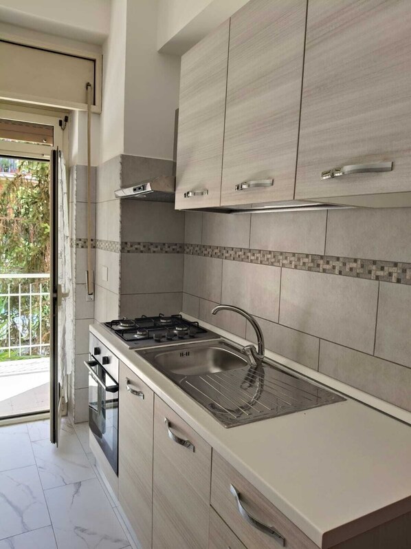 A modern kitchen with a gas stove, stainless steel sink, and light wood cabinetry. - Delightful Rome apartment -Vatican 9' from the Battistini metro (Roma)
