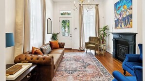 A living room with a brown sofa, blue armchair, and a patterned rug. - Hi-End Historic Marigny Gem - Fully Furnished with 2 Bonus Office Space (New Orleans)