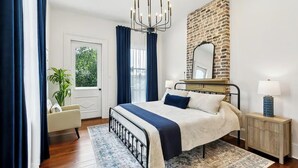 A bedroom with a large bed, a chandelier, a mirror, a nightstand, and a view of the outdoors. - Hi-End Historic Marigny Gem - Fully Furnished with 2 Bonus Office Space (New Orleans)