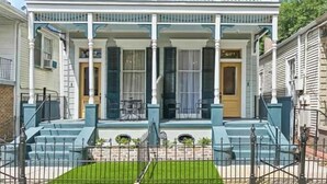 A two-story building with a balcony, a front porch with chairs, and a small garden area. - Hi-End Historic Marigny Gem - Fully Furnished with 2 Bonus Office Space (New Orleans)