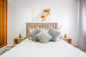 A bedroom with a large bed, a wooden headboard, and two bedside tables with lamps.
