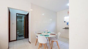Une cuisine moderne avec des carreaux blancs, une table à manger entourée de chaises et une petite fenêtre au-dessus de l’évier.