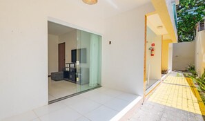 A modern hotel entrance with a glass door leading to a room, a fire extinguisher on the wall, and a yellow-tiled pathway outside. - Apt w/ Balcony & BBQ 400m From sea Rbr0003 (Salvador)