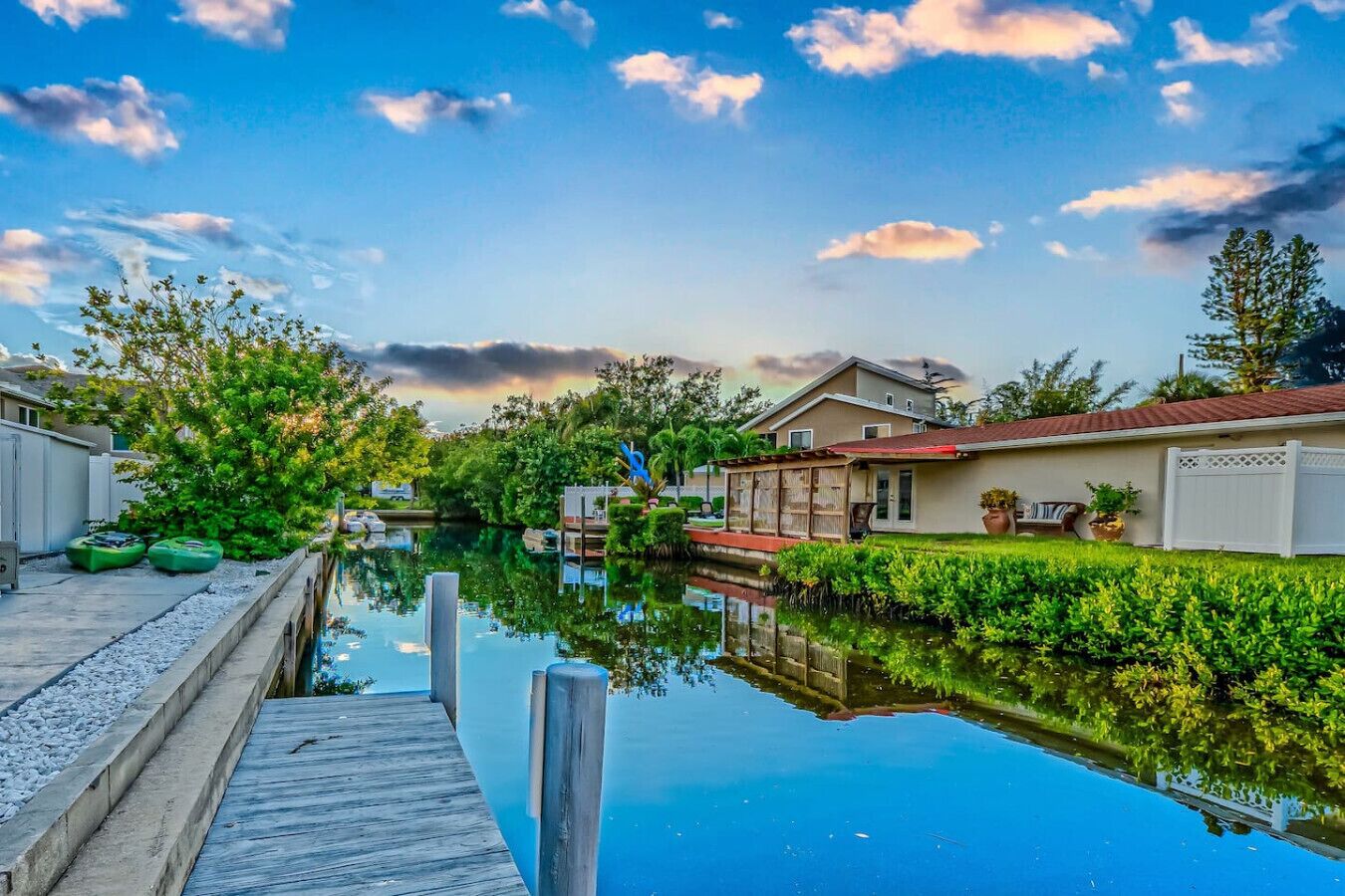 A canal with a wooden dock, houses on one side, and a clear sky.