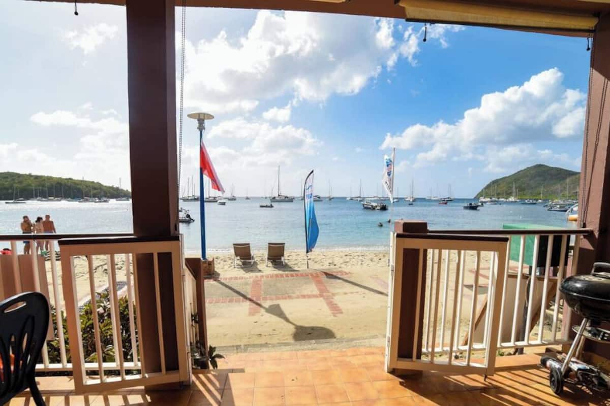 Una terraza con vista al mar, con una parrilla y mobiliario exterior.