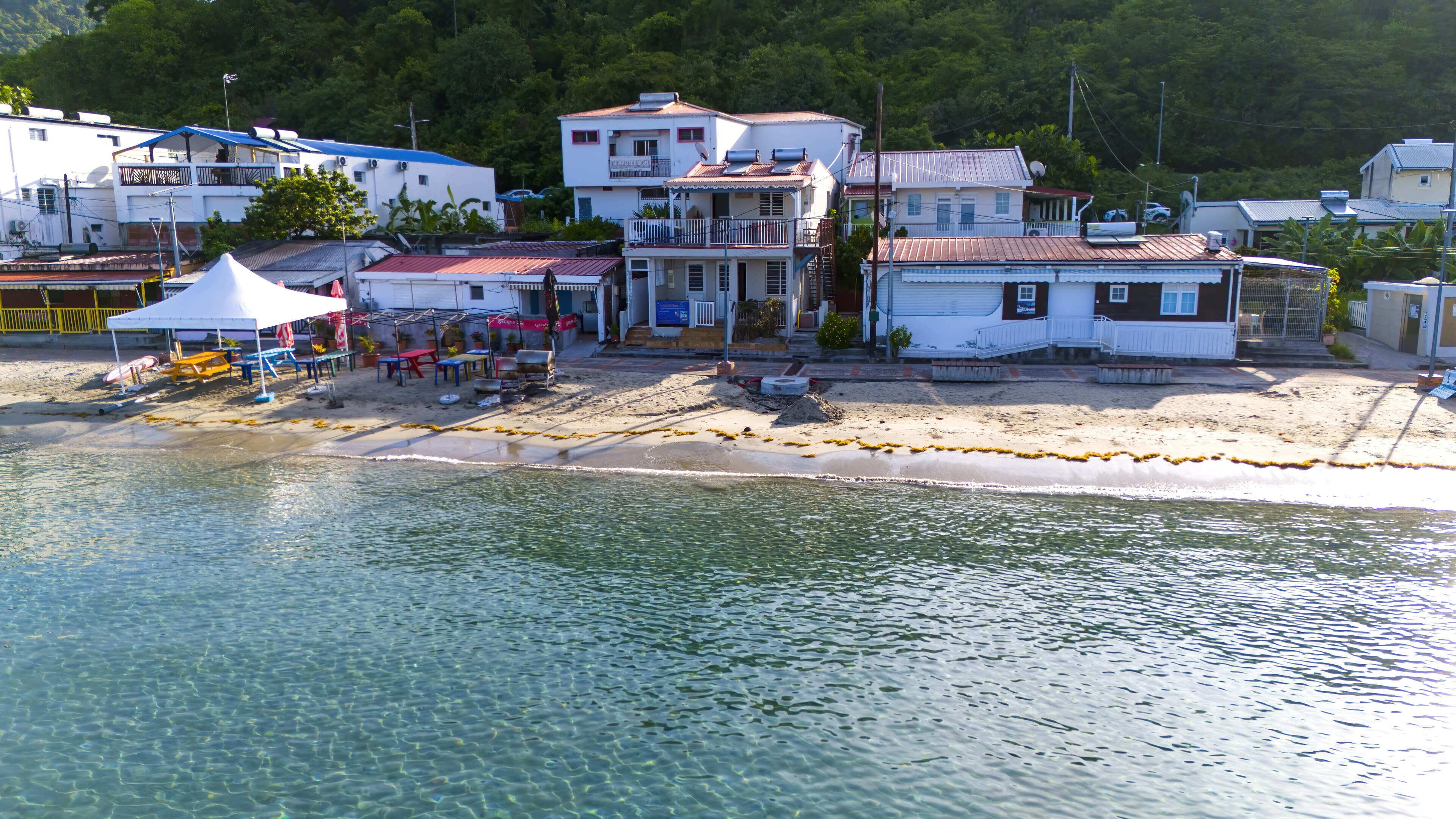 Una zona costera con edificios, una playa arenosa y agua cristalina.