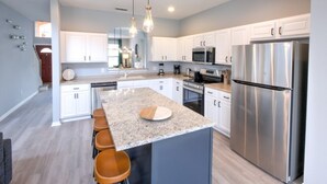 A modern kitchen with a central island, stainless steel appliances, and pendant lighting.