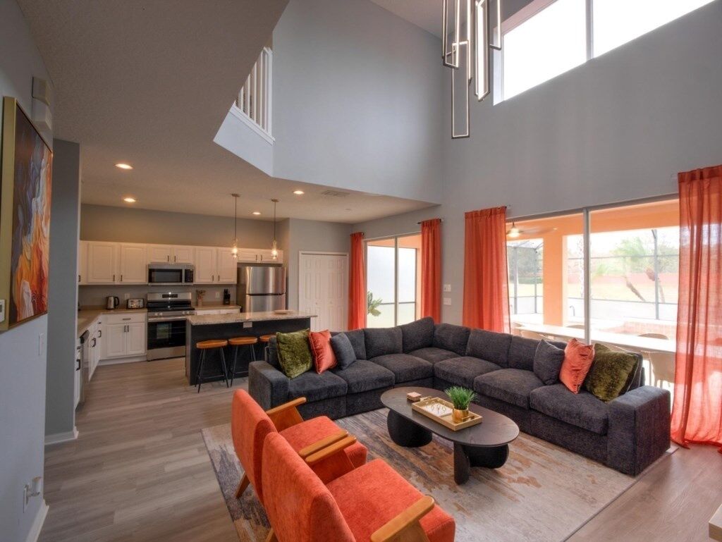 A spacious living area with a large sectional sofa, a coffee table, and a kitchen in the background.