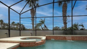 A swimming pool with a hot tub, surrounded by a metal frame and palm trees.