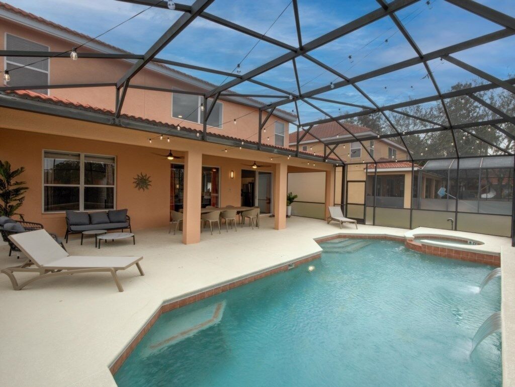 An indoor swimming pool with lounge chairs and a covered patio area.