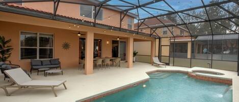 An indoor swimming pool with lounge chairs and a covered patio area.