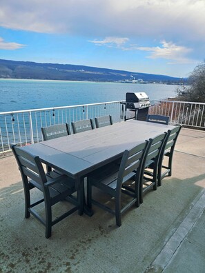 Eine Terrasse mit Tisch und Stühlen mit Blick auf ein Gewässer.