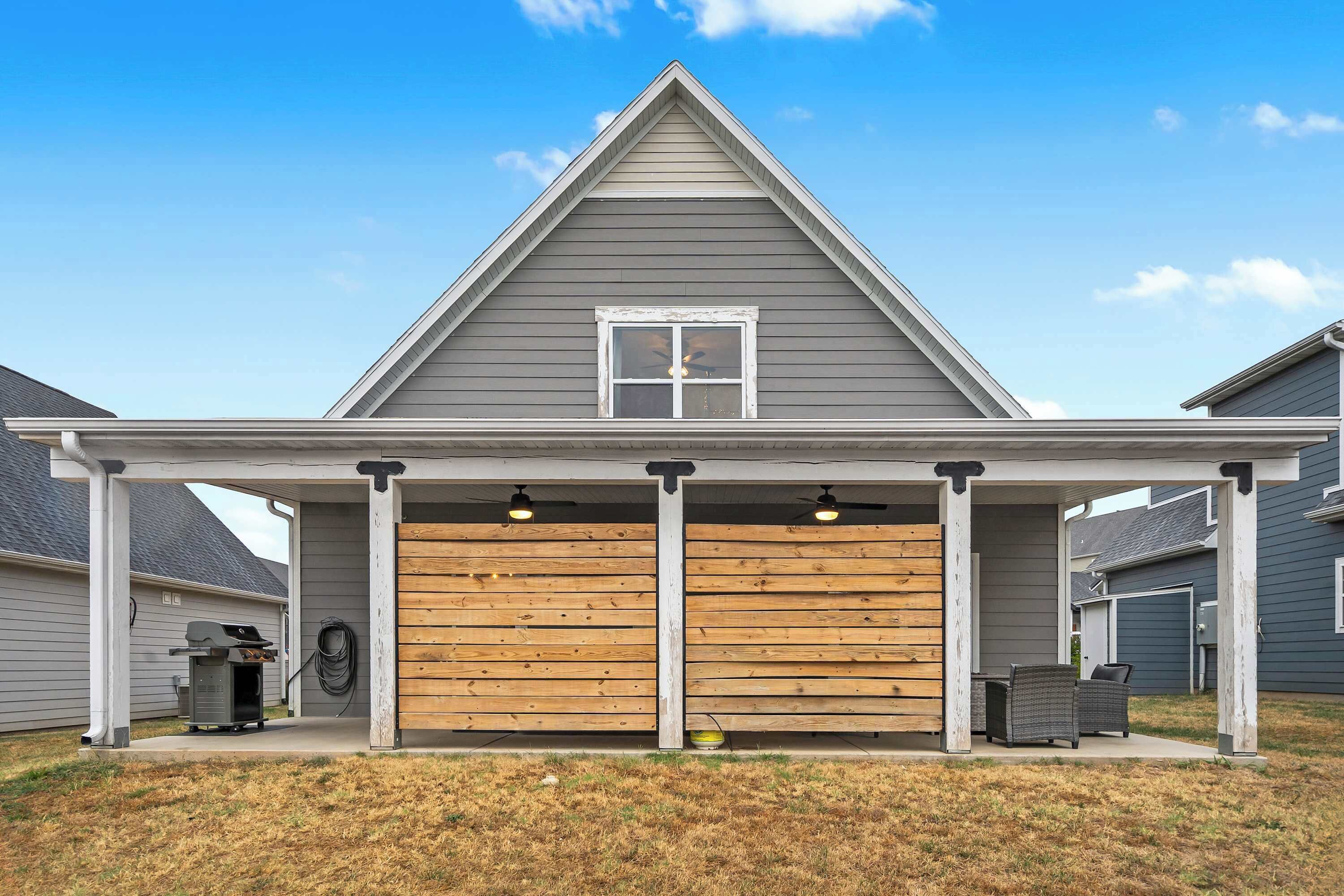 A house with a covered garage, a grill, and a patio with chairs.