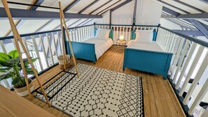 Une pièce aménagée comme une tente, avec deux lits, un tapis à motifs et une plante en pot.