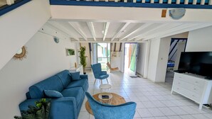 Un salon spacieux avec un canapé bleu, une table basse ronde et un meuble pour la télévision.