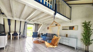 Un vaste espace de vie comprenant un fauteuil suspendu, un canapé et une table à manger.