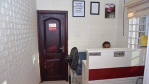 A reception area with a wooden door marked "No Smoking" and "Toilets," a fan, and a sign indicating WiFi availability. - Terra Santa Lodgings & Restaurants (Adentan)