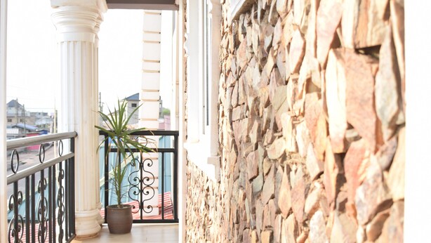 A balcony with stone walls, a potted plant, and a view of the city. - Terra Santa Lodgings & Restaurants (Adentan)
