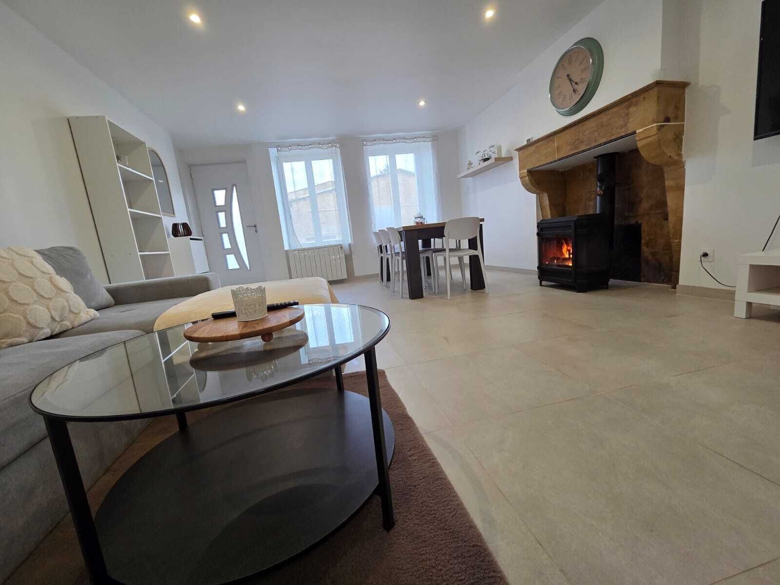 Una sala moderna con una mesa de centro de vidrio, un sofá, una chimenea y un comedor.