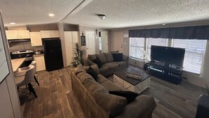 A compact living space with a kitchenette, a sofa, a coffee table, and a television.