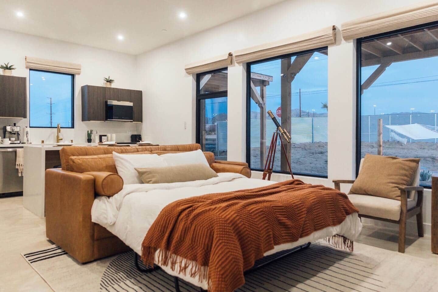 A modern bedroom with a large bed, a seating area, and a view of the beach.
