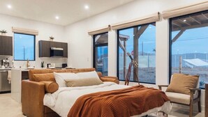 Ein modernes Schlafzimmer mit einem großen Bett, einer Sitzecke und Blick auf den Strand.