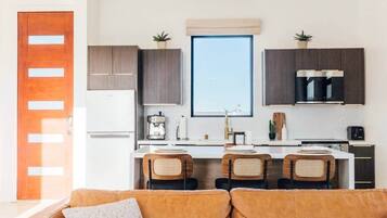 A compact kitchen with a central island, two bar stools, and a window above the sink.