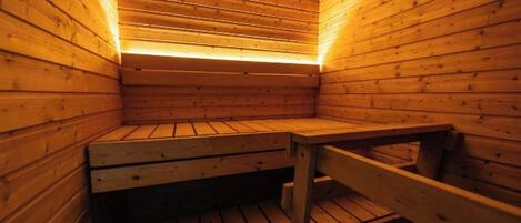 A sauna with wooden benches and a sloped ceiling.