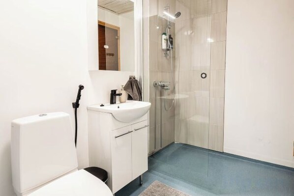 A bathroom with a toilet, sink, and shower. - Cozy Koivutie Apartment (Ranua)