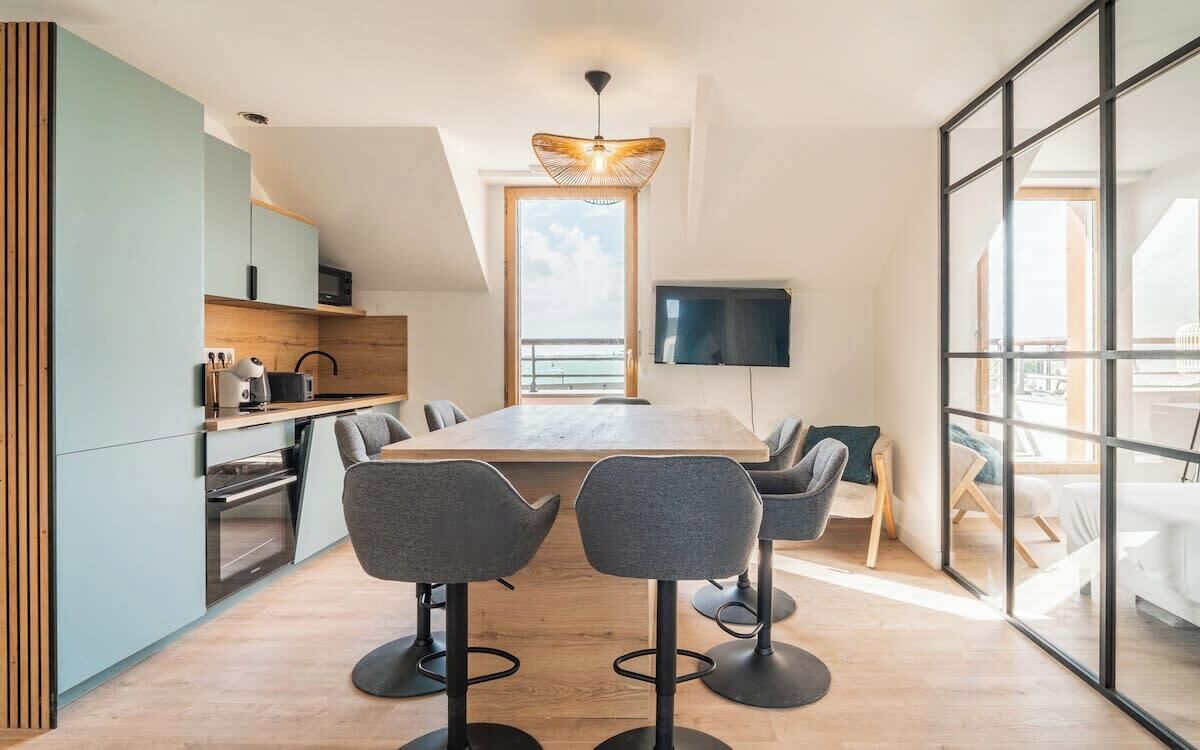 Una cocina moderna con comedor, televisor y balcón con vistas.