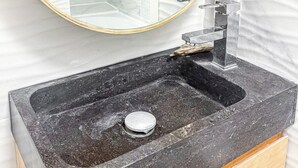 A bathroom with a round mirror, black sink, and white tiled walls.