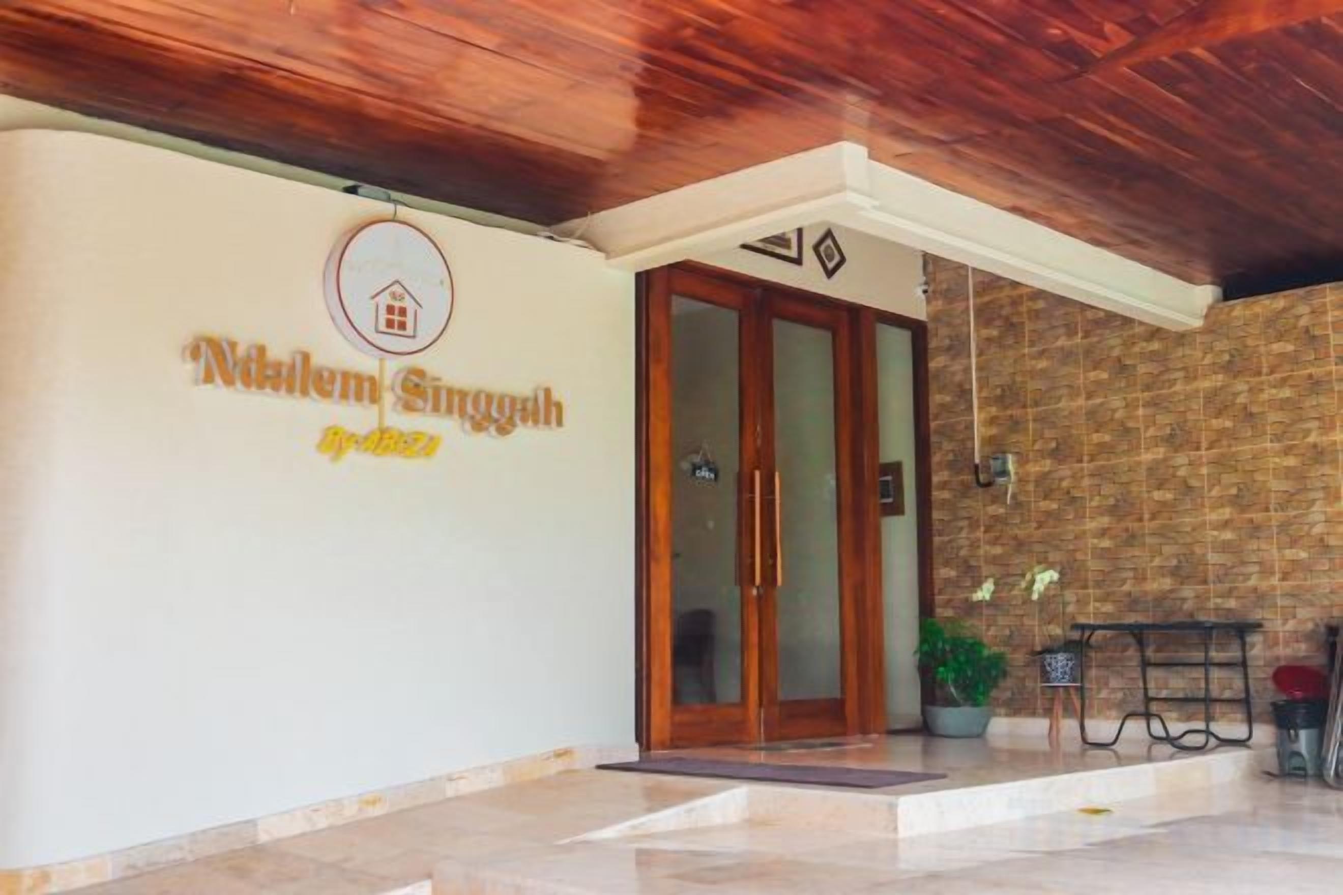 A hotel entrance with a sign reading 'Niklem Singgah' and a wooden ceiling.
