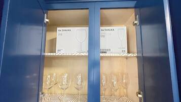 A blue cabinet with two shelves, each containing a box labeled '6x SVALKA' and a pair of wine glasses.