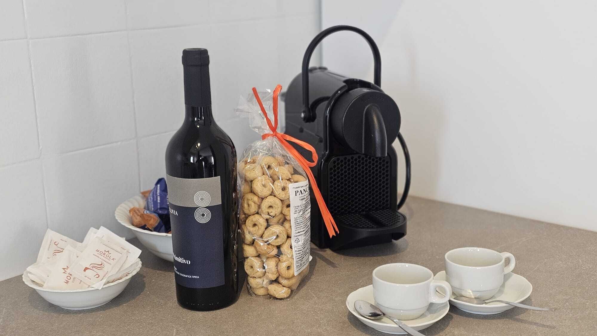 Une bouteille de vin, un paquet de biscuits, un haut-parleur portable et deux tasses sur un comptoir.