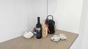 A kitchen counter with a wine bottle, a bag of cookies, a coffee maker, and two cups on a beige countertop. - Dimora Peppino, a family friendly holiday home, just few step from the sea. (Polignano a Mare)