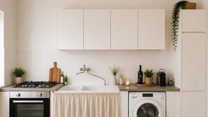 A kitchen with a gas stove, oven, sink, and washing machine. - Dimora Peppino, a family friendly holiday home, just few step from the sea. (Polignano a Mare)