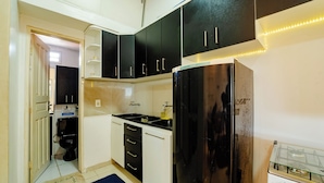A compact kitchen with black cabinets, a stainless steel refrigerator, and a gas stove.